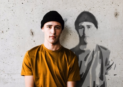 Hipster poses next to his image stenciled on a wall